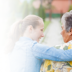 Caregiver embracing an older woman with dementia outdoors